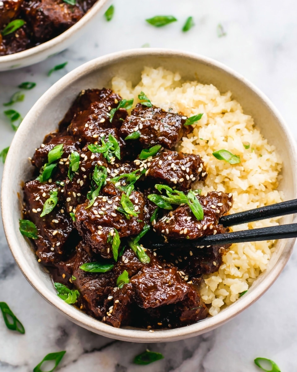 The image shows a white bowl filled with two main layers: the bottom layer of pale yellow cooked rice with a slightly fluffy texture, and the top layer of dark brown glazed beef pieces coated in a shiny sauce, giving them a rich and thick look. The beef is sprinkled with white and black sesame seeds and garnished with bright green chopped scallions. Black chopsticks are placed inside the bowl, holding some beef. The bowl sits on a white marbled surface with scattered green scallion pieces around it. Photo taken with an iphone --ar 4:5 --v 7