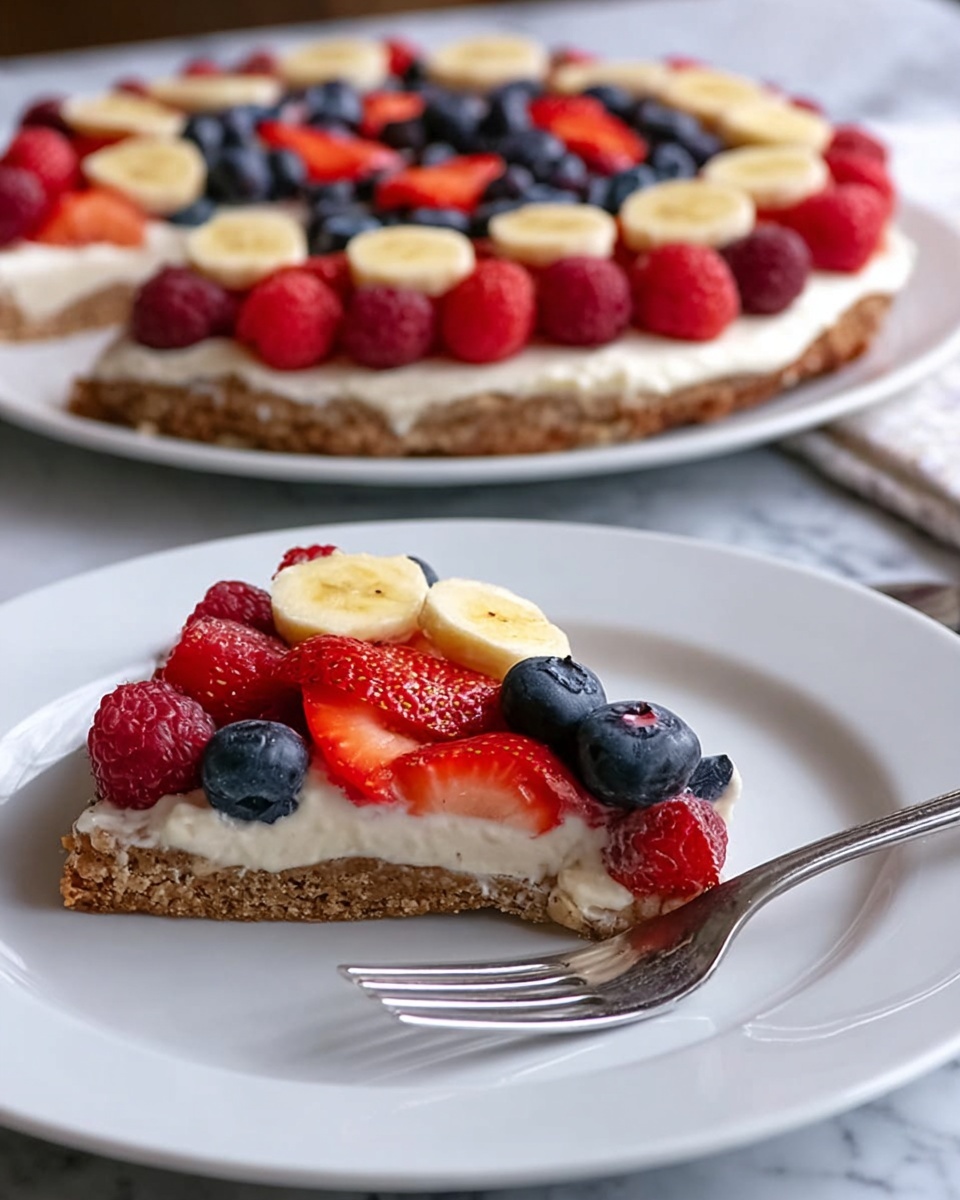 Oat and Yogurt Fruit Pizza Recipe 5 The image shows a slice of fruit pizza on a white plate with a silver fork beside it. The fruit pizza has three layers: a brown crust at the bottom with a slightly rough texture, a thick white creamy layer in the middle, and a colorful fruit topping arranged on top. The fruit layer includes bright red strawberry slices placed along the edge, dark red raspberries, dark blue blueberries, and round yellow banana slices spread evenly across the creamy layer. In the background, there is the remaining portion of the fruit pizza on a larger white plate, sitting on a white marbled surface. Photo taken with an iphone --ar 4:5 --v 7