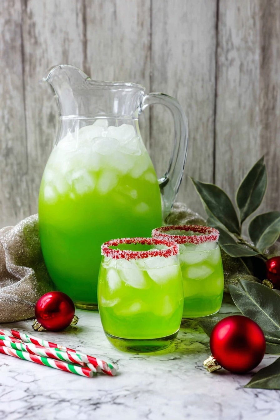 A clear glass pitcher filled with bright green liquid and lots of ice cubes sits on a white marbled textured surface. In front of the pitcher, there are two white clear glasses filled with the same green drink and ice cubes, each glass has a red sugared rim. Next to the glasses are three striped paper straws in red, white, and green colors. To the side, some green leaves and red Christmas ornaments add a festive touch. The background shows a rustic wooden wall in soft gray tones. photo taken with an iphone --ar 2:3 --v 7 - Festive Grinch Punch, green holiday punch, Christmas party drinks, holiday festive drinks, easy holiday punch