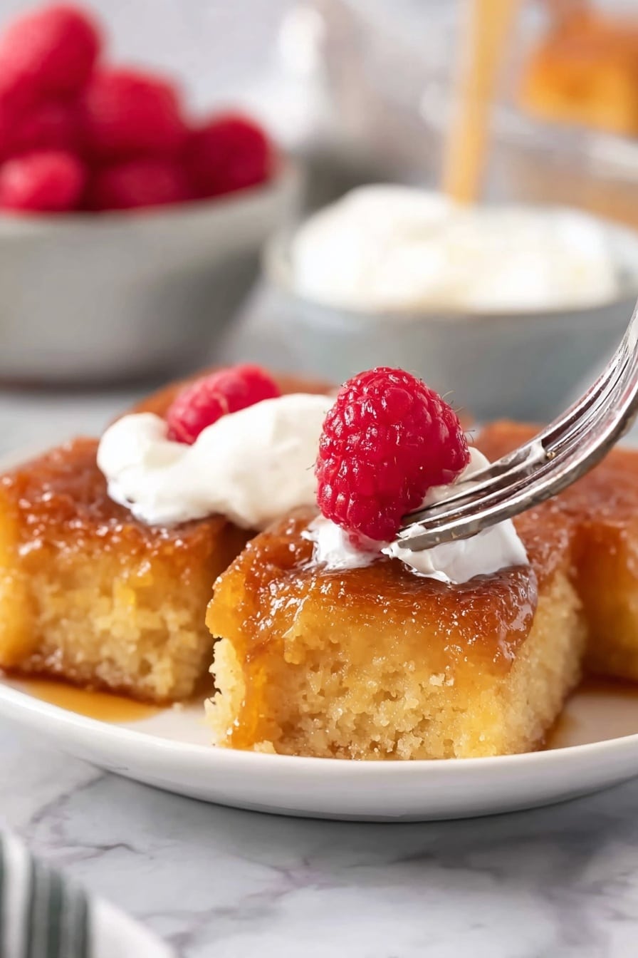 The image shows a close-up of a dessert on a white plate placed on a white marbled surface. The bottom layer is a golden brown, soft bread pudding with a slightly crispy texture and syrup drizzled over it, giving it a shiny look. On top of this layer is a dollop of white whipped cream, smooth and fluffy. Two bright red raspberries sit on the whipped cream near the top-right side, adding a fresh and juicy contrast to the warm tones below. In the blurry background, a basket filled with more red raspberries is visible. photo taken with an iphone --ar 2:3 --v 7 - Overnight Creme Brûlée French Toast Bake, French Toast Breakfast Ideas, Easy Overnight French Toast, Caramelized French Toast Casserole, Brunch Recipes with Creme Brûlée