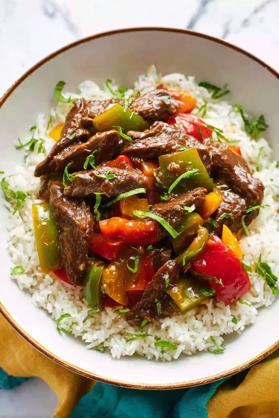 A white bowl filled with a base layer of fluffy white rice, topped with a vibrant mix of glossy, dark brown beef strips and chunky pieces of red, green, and yellow bell peppers. The dish is garnished with small green herb leaves scattered on top. The bowl sits on a white marbled surface with a soft yellow and green cloth partially visible beside it. photo taken with an iphone --ar 2:3 --v 7 - Pepper Steak and Onions Stir Fry, stir fry dinner ideas, quick beef stir fry, healthy beef stir fry recipe, easy weeknight stir fry