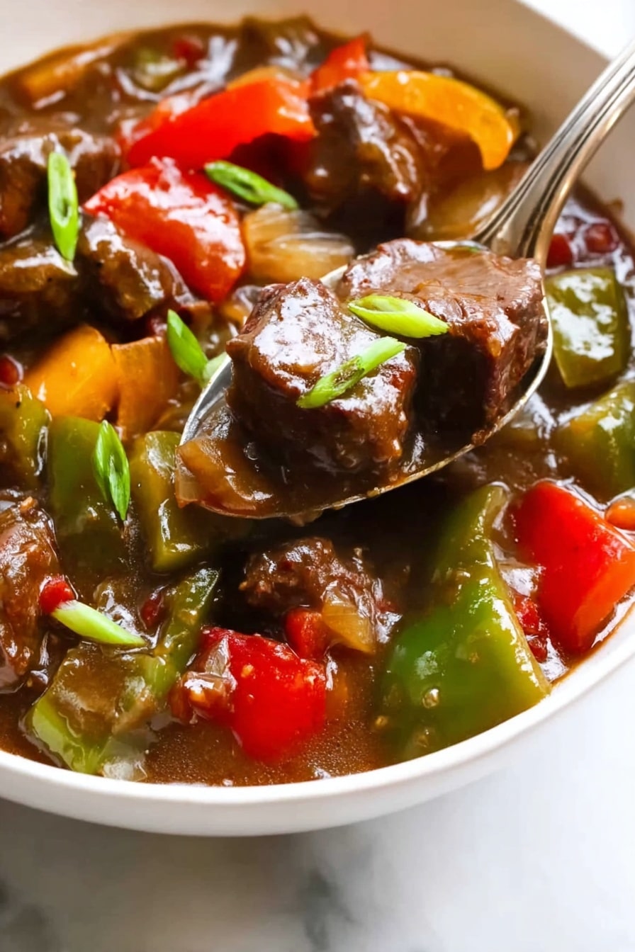 The image shows a close-up of a white bowl filled with a colorful stew featuring chunks of dark brown beef, bright green and red bell pepper pieces, yellow bell pepper chunks, and translucent onions all mixed in a thick brown sauce. A silver spoon rests inside the bowl and holds a piece of beef covered in sauce. There are small green onion slices scattered throughout, adding a fresh touch. The bowl sits on a white marbled surface with soft natural light highlighting the glossy textures of the meat and vegetables. Photo taken with an iphone --ar 2:3 --v 7 - Pepper Steak and Onions Stir Fry, stir fry dinner ideas, quick beef stir fry, healthy beef stir fry recipe, easy weeknight stir fry