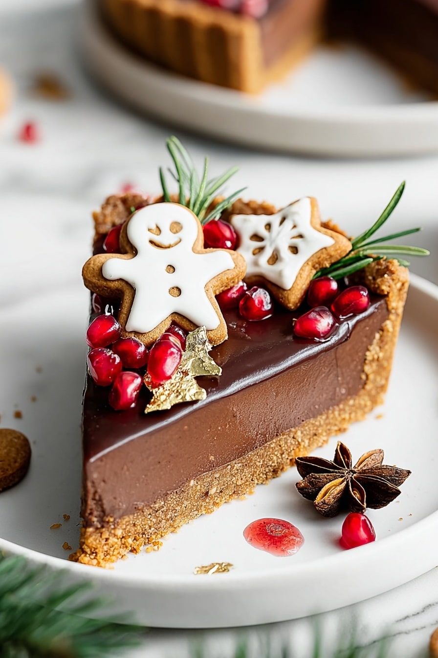 A slice of rich chocolate tart with three visible layers: a crumbly golden crust at the bottom, a thick smooth dark chocolate filling in the middle, and a glossy chocolate top layer. The tart slice is decorated on top with small gingerbread cookies, one shaped like a smiling person with white icing and the other like a white star. Around the cookies are pomegranate seeds, red and shiny, green rosemary sprigs, and a brown star anise placed near the front. There are a few gold leaf pieces scattered on top for shine. The slice rests on a white plate with a few red juice drops and crumbs. The background is a white marbled texture with blurred parts of the tart in the back, and a blurred green pine branch is visible in the lower corner. Photo taken with an iphone --ar 2:3 --v 7 - Vegan Gingerbread Chocolate Tart, plant-based holiday desserts, festive vegan desserts, gingerbread chocolate tart, dairy-free chocolate tart recipe
