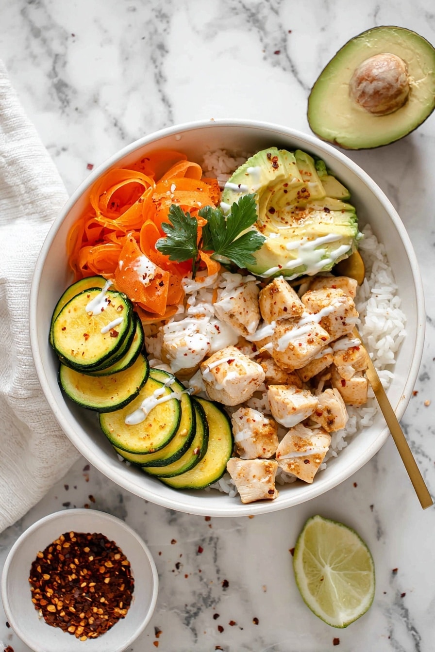 Hot Honey Chicken Rice Bowls Recipe 8 The dish is served in a white bowl filled with a base layer of white rice, topped with several sections: cooked round slices of green and yellow zucchini arranged along one side, shredded orange carrots with a parsley leaf on top, several pieces of cooked cubed chicken covered lightly with a white sauce and chili flakes, and three slices of fresh light green avocado. A wedge of lime lies on the rice next to the avocado. The bowl is placed on a white marbled surface with a small white bowl of chili flakes nearby. A gold spoon rests inside the bowl by the carrots and chicken, and a drizzle of white sauce is seen over the chicken and zucchini. Photo taken with an iphone --ar 2:3 --v 7 - Hot Honey Chicken Bowls, Hot Honey Chicken Rice Bowls, spicy honey chicken, easy chicken rice bowls, flavorful dinner ideas
