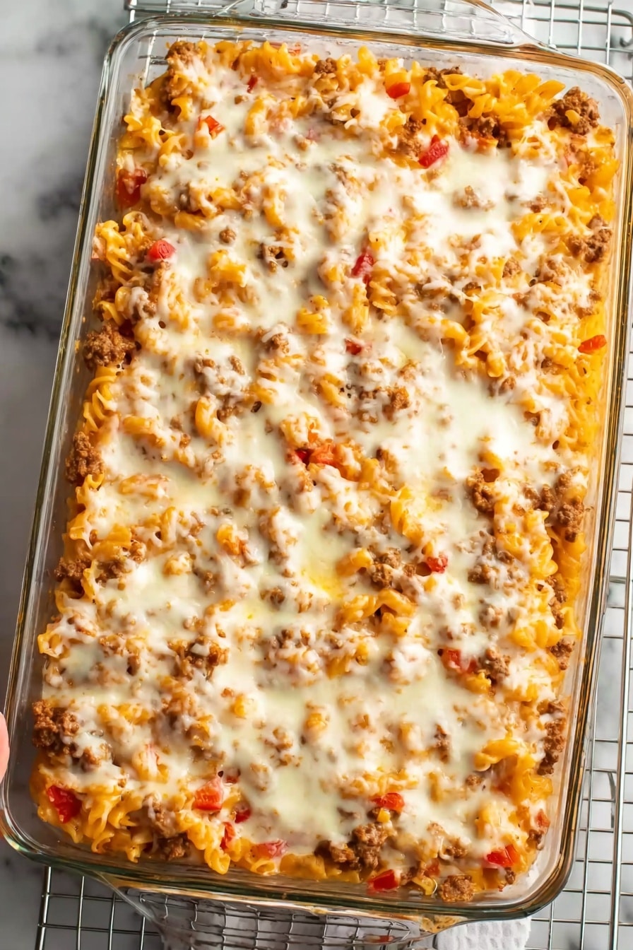 Cheeseburger Casserole Recipe 8 The image shows a close-up of a cheesy pasta dish being lifted by a spoon. The dish has three main layers: the bottom layer is pasta with a mix of cooked ground meat, the middle layer is melted white cheese stretching upwards in long, thin strings, and the top layer is melted orange cheese bubbling and blending into the white cheese. The texture is soft and creamy with visible bits of meat spread evenly throughout. The background features a white marbled surface with a blurred dark kitchen cloth in the back. Photo taken with an iphone --ar 2:3 --v 7 - Cheeseburger Casserole, cheeseburger casserole recipe, easy cheeseburger casserole, comforting dinner ideas, one-pan ground beef casserole