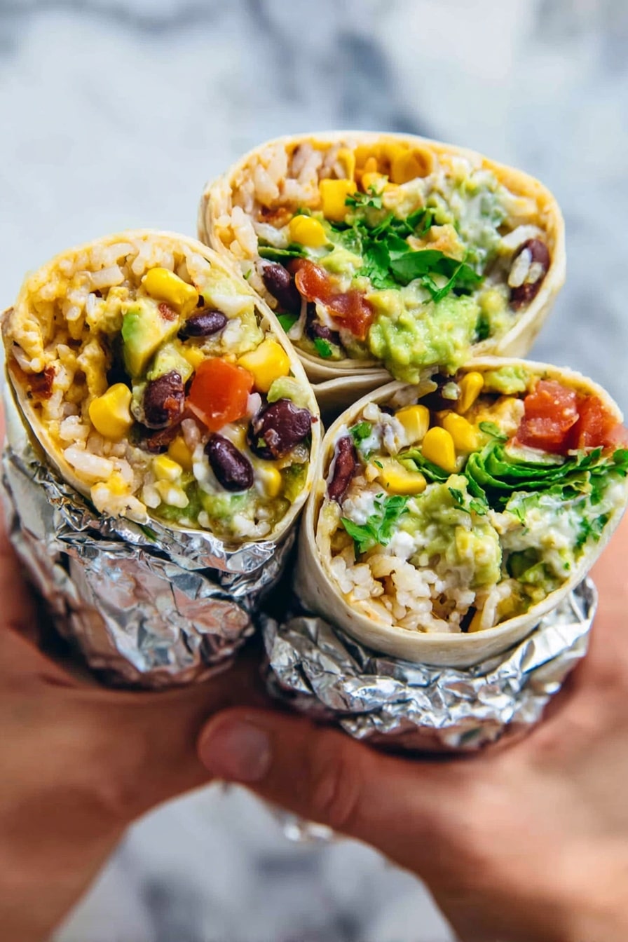 Vegan Black Bean Burrito Recipe 6 Three burrito halves held by a woman's hand, each wrapped in a white tortilla and partially covered in shiny silver foil at the bottom. Inside, layers include light brown rice, bright yellow corn kernels, dark black beans, chunks of red tomato, vivid green pieces of lettuce or other greens, creamy light green guacamole, and white sour cream. The burritos look fresh and full of color, with the ingredients tightly packed and visible from the open ends. The background is a white marbled surface. Photo taken with an iphone --ar 2:3 --v 7 - Vegan Black Bean Burrito, Vegan Black Bean Wrap, Healthy Vegan Burrito, Easy Vegan Dinner, Vegetarian Burrito Ideas