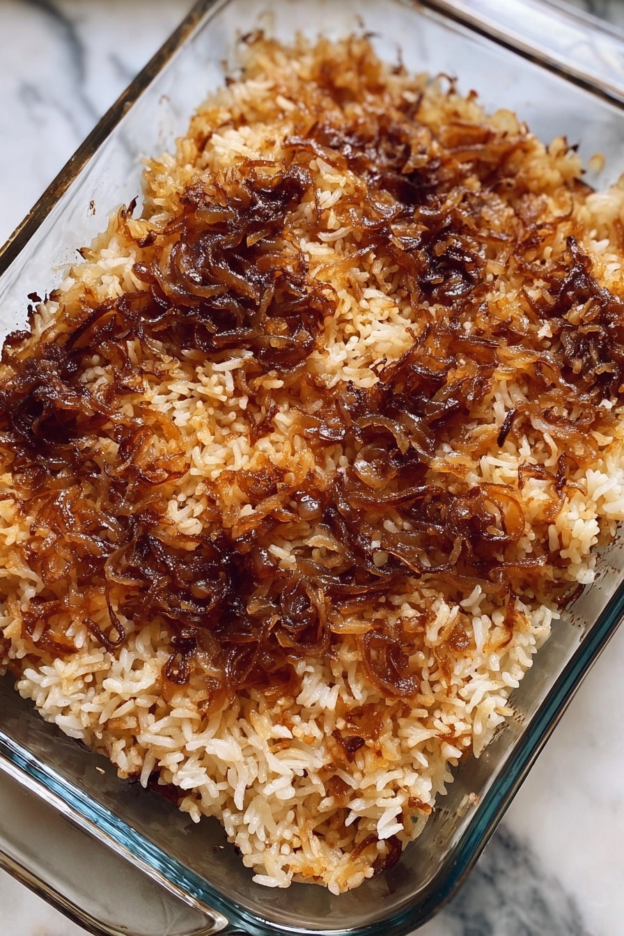 A close-up of a white bowl filled with cooked rice that has a light brown color with darker brown spots mixed in. The rice grains are soft and slightly sticky, with a textured look from the small bits of darker ingredients scattered throughout. The bowl is placed on a white marbled surface with part of a yellow cloth visible at the bottom right corner. The background shows out-of-focus green, suggesting it is outdoors or near plants. Photo taken with an iphone --ar 2:3 --v 7 - French Onion Soup Rice Bake, French Onion Soup casserole, onion soup rice bake, easy French onion bake, comforting onion rice dish