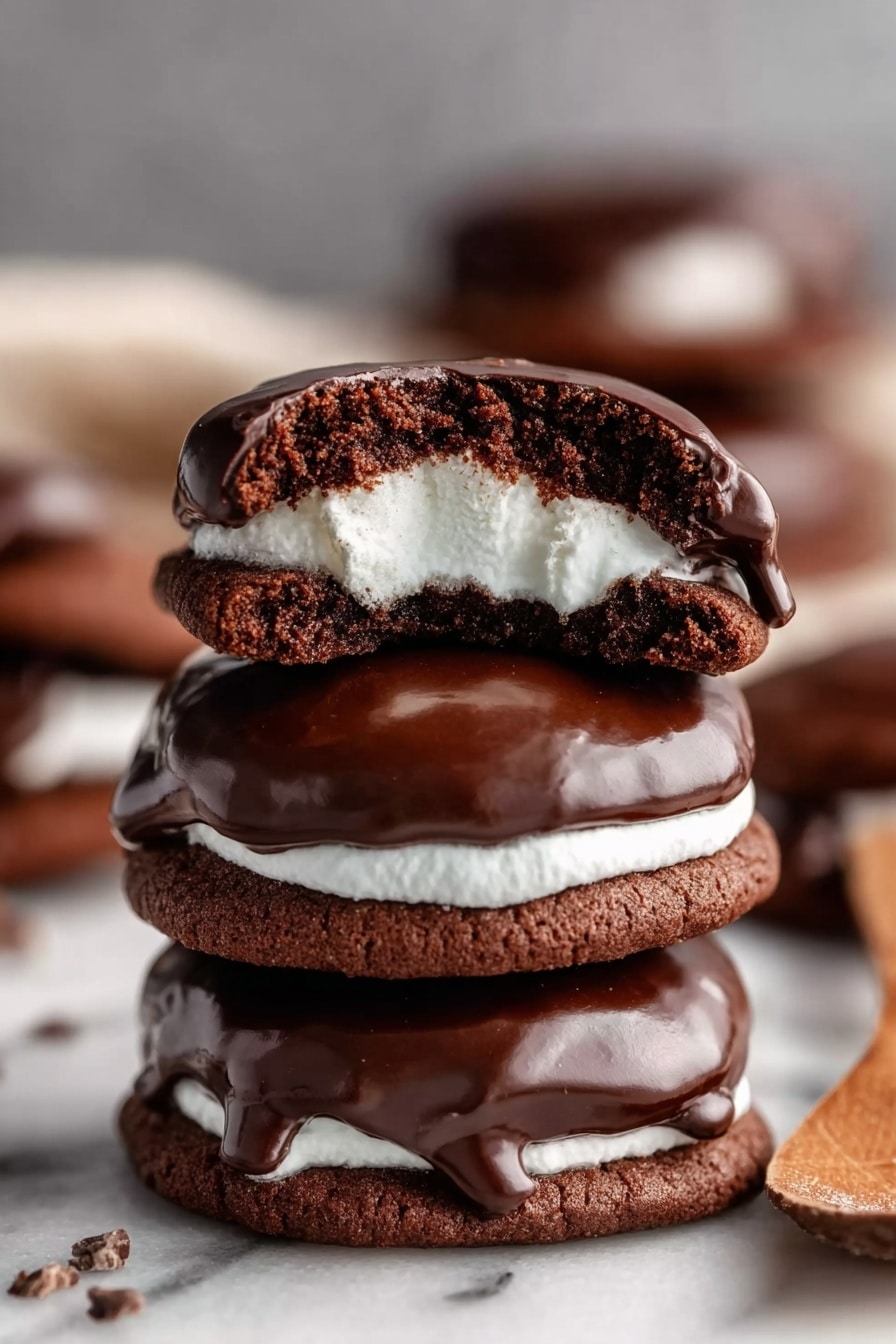 Marshmallow Hot Cocoa Cookies Recipe 6 The image shows a stack of four dark brown chocolate cookies with a smooth, shiny layer of melted chocolate on top of each cookie. The top cookie is broken in half, revealing a soft white marshmallow layer inside that contrasts with the dark cookie and chocolate. The cookies have a rich, slightly rough texture, and they sit on a white marbled surface. The background is softly blurred, keeping the focus on the stacked cookies. photo taken with an iphone --ar 2:3 --v 7 - Marshmallow Hot Cocoa Cookies, hot cocoa cookies, marshmallow cookies, chocolate marshmallow treats, cozy holiday cookies