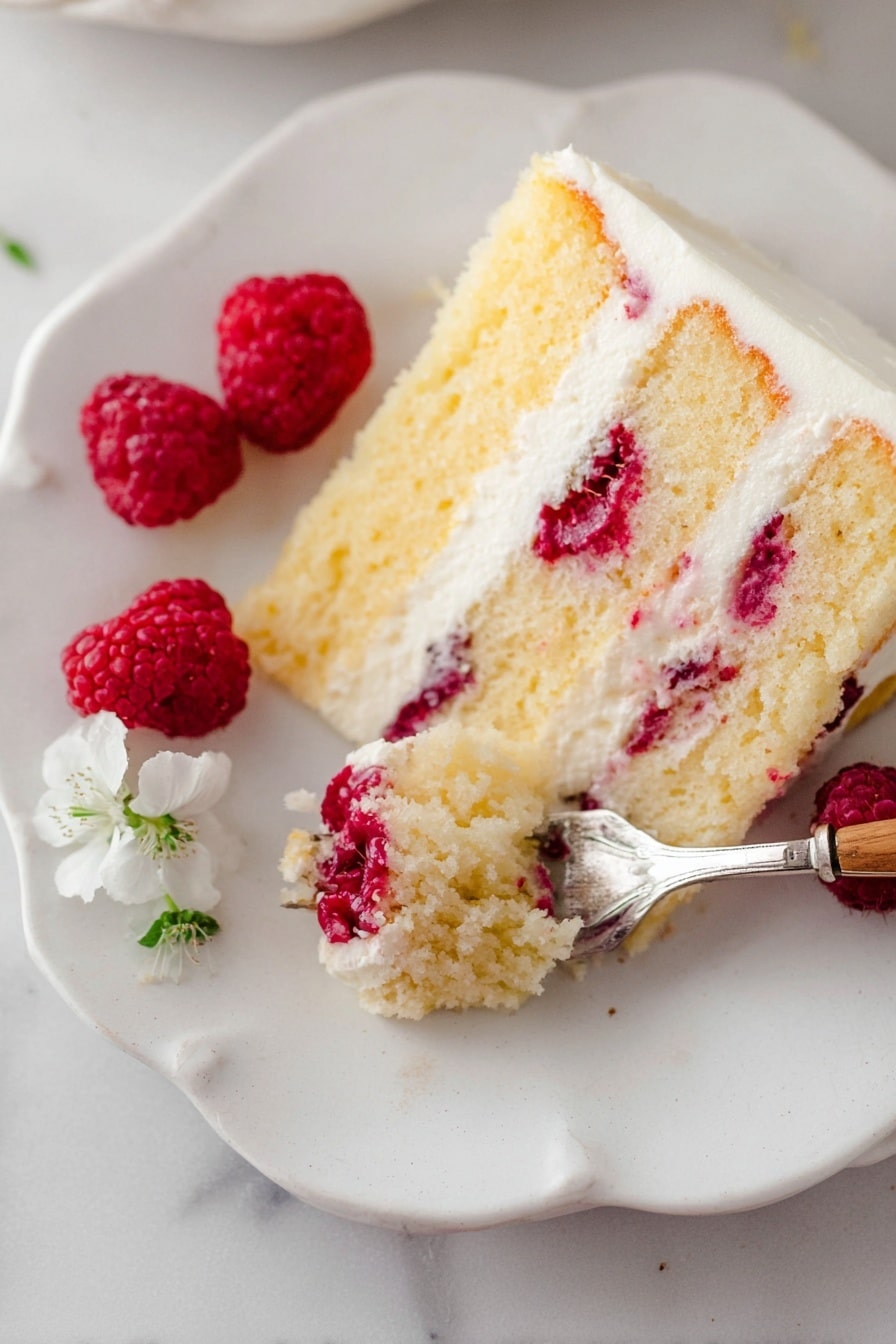 Lemon Raspberry Cake with Cream Cheese Frosting Recipe 8 A slice of yellow cake with three layers is shown on a white plate with scalloped edges, placed on a white marbled surface. The cake has bright red raspberries embedded inside the moist layers, separated by smooth white cream layers. A silver fork with a wooden handle holds a bite of the cake, revealing the soft texture and raspberry pieces in the bite. Three fresh raspberries and a small white flower are placed near the cake slice on the plate. The photo taken with an iphone --ar 2:3 --v 7 - Lemon Raspberry Cake with Cream Cheese Frosting, lemon raspberry cake recipe, moist raspberry cake, creamy frosting cake, citrus berry layer cake