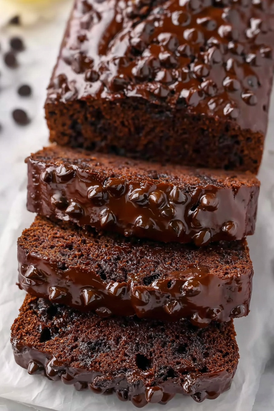 Healthy Banana Chocolate Bread Recipe 6 This image shows a loaf of chocolate bread with five thick slices stacked slightly on top of each other on white parchment. The bread is dark brown with a moist texture and embedded chocolate chips. The top of each slice is covered with a glossy layer of melted chocolate and sprinkled with more chocolate chips, giving a rich and shiny look. The background is a white marbled surface. photo taken with an iphone --ar 2:3 --v 7 - Healthy Banana Chocolate Bread, healthy banana bread, moist banana bread, gluten-free banana bread, nutritious chocolate banana loaf