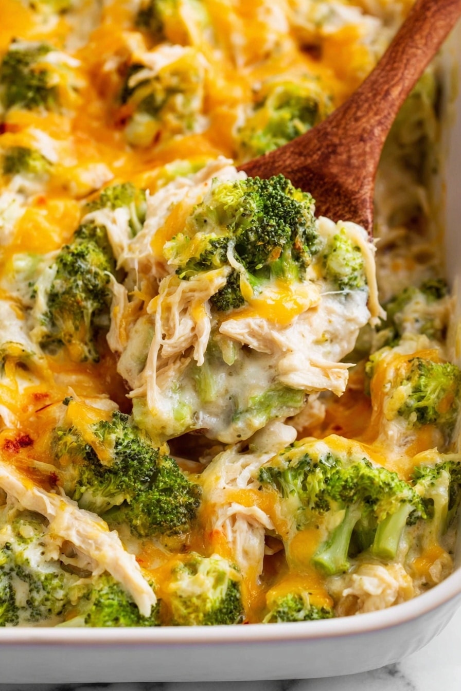 Chicken Bacon Ranch Casserole Recipe 6 The image shows a dish with a base layer of cooked chicken pieces mixed with bright green broccoli florets, all covered in a creamy white sauce. On top of this, there is a layer of melted shredded cheese that is mostly yellow with some white cheese strands, adding a slightly crispy texture in some areas. The dish is being served with a wooden spoon, scooping a portion from a white ceramic baking dish. The background surface is a white marbled texture. photo taken with an iphone --ar 2:3 --v 7 - Chicken Bacon Ranch Casserole, Chicken Bacon Ranch Bake, Easy Chicken Casserole, Cheesy Chicken Bake, Fast Weeknight Dinners