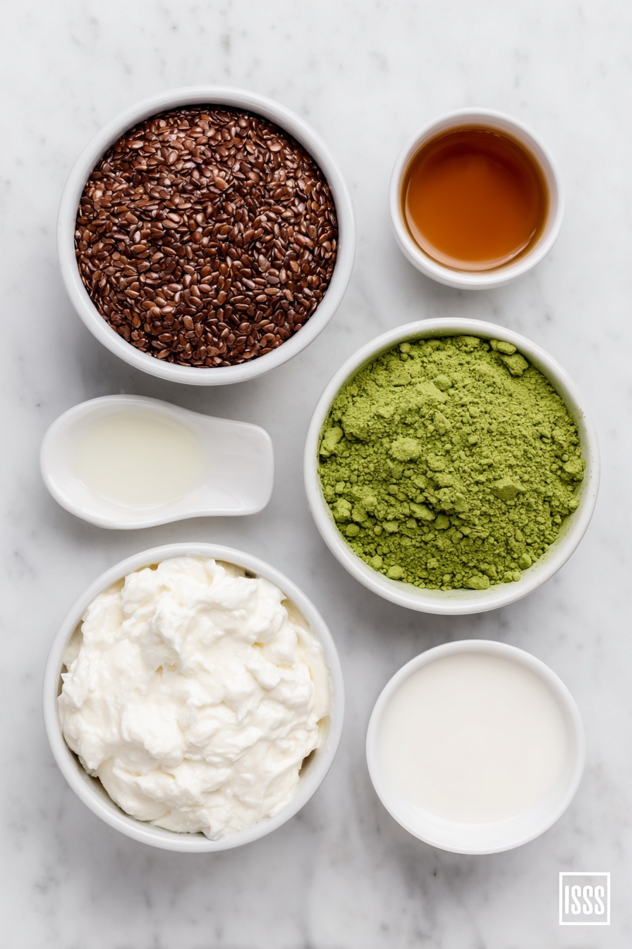 Matcha Chia Pudding Recipe 7 Flat lay of a small white ceramic bowl filled with dry chia seeds, a small white bowl with creamy full-fat coconut milk, a small white bowl with unsweetened almond milk, a white ceramic spoon holding vibrant green matcha powder, a tiny white bowl with golden pure maple syrup, and a small white bowl with clear vanilla extract liquid, all arranged symmetrically with natural lighting and no packaging or utensils, placed on a clean white marble surface, soft natural light, photo taken with an iPhone, professional food photography style, fresh ingredients, white ceramic bowls, no bottles, no duplicates, no utensils, no packaging --ar 2:3 --v 7 --p m7354615311229779997 - Matcha Chia Pudding, healthy chia pudding recipe, vegan matcha breakfast, antioxidant-rich chia pudding, easy matcha chia dessert