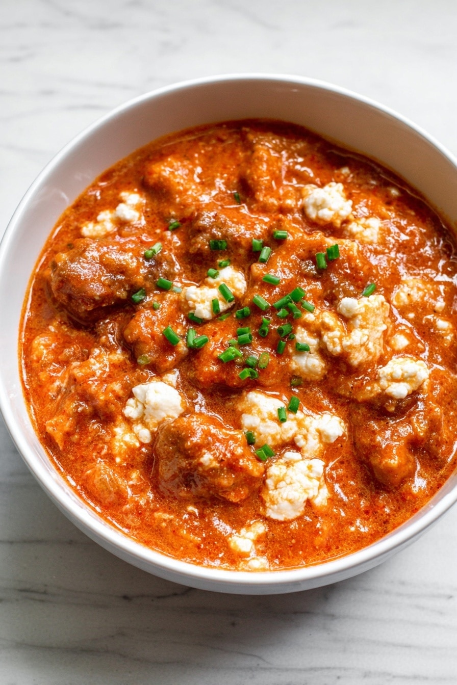 The image shows a white bowl filled with a thick mix of orange-red sauce coating small white curd-like pieces and chopped green herbs. The sauce looks creamy and slightly chunky, with the white bits spread evenly through the mixture, making it look textured and rich. A gold spoon is partially visible on the right side, partly dipped into the bowl. The bowl sits on a white marbled surface. photo taken with an iphone --ar 2:3 --v 7 - High Protein Cottage Cheese Chicken Parm Bowl, healthy chicken parm bowl, quick protein-packed dinner, cottage cheese chicken recipe, easy high-protein meal