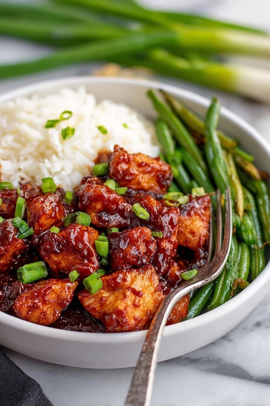 Honey Butter Chicken Skillet Recipe 6 The image shows a white bowl filled with three visible layers: a base layer of white rice on the left, a middle layer of green beans towards the back right, and a top layer of dark reddish-brown glazed chicken pieces sprinkled with chopped green onions in the foreground. A fork rests on the right side of the bowl, partially on the green beans. The bowl is placed on a white marbled surface with a blurred background that includes some green onions. Photo taken with an iphone --ar 2:3 --v 7 - Honey Butter Chicken Skillet, easy chicken dinner, quick skillet chicken, flavorful chicken recipes, one-pan chicken meal